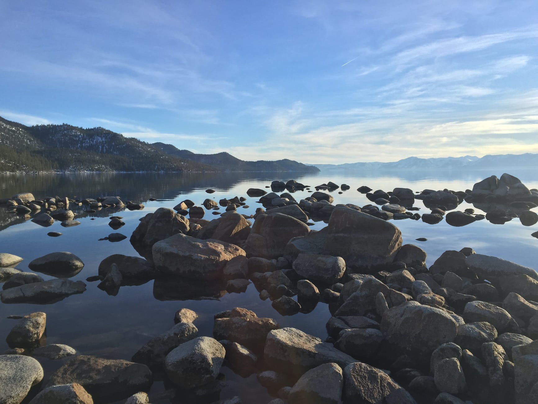 Stones in lake under partly cloudy sky