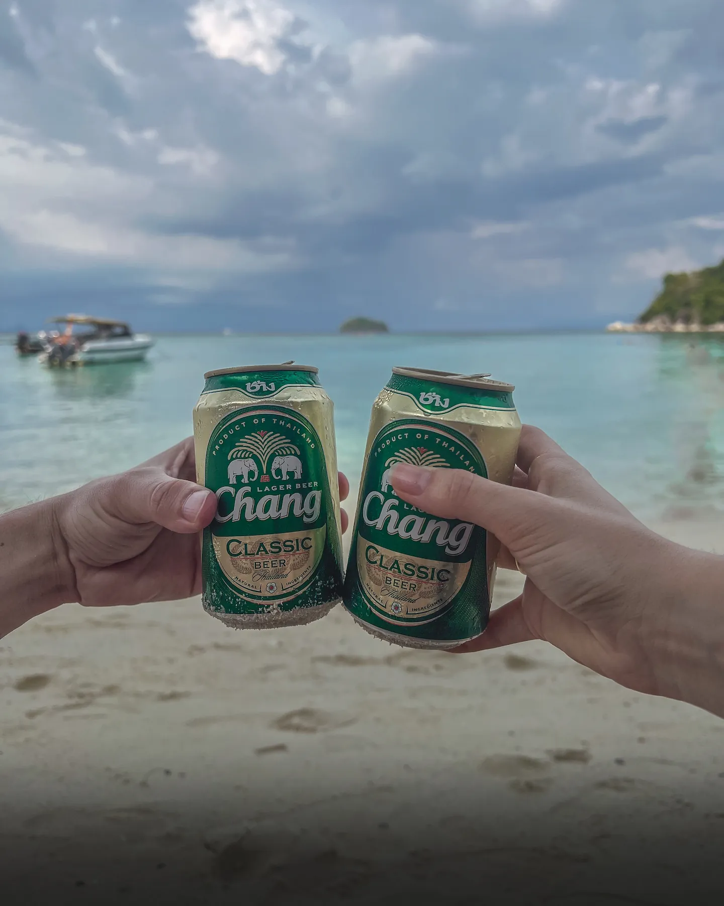 Cheers with cans of Chang beer at beach
