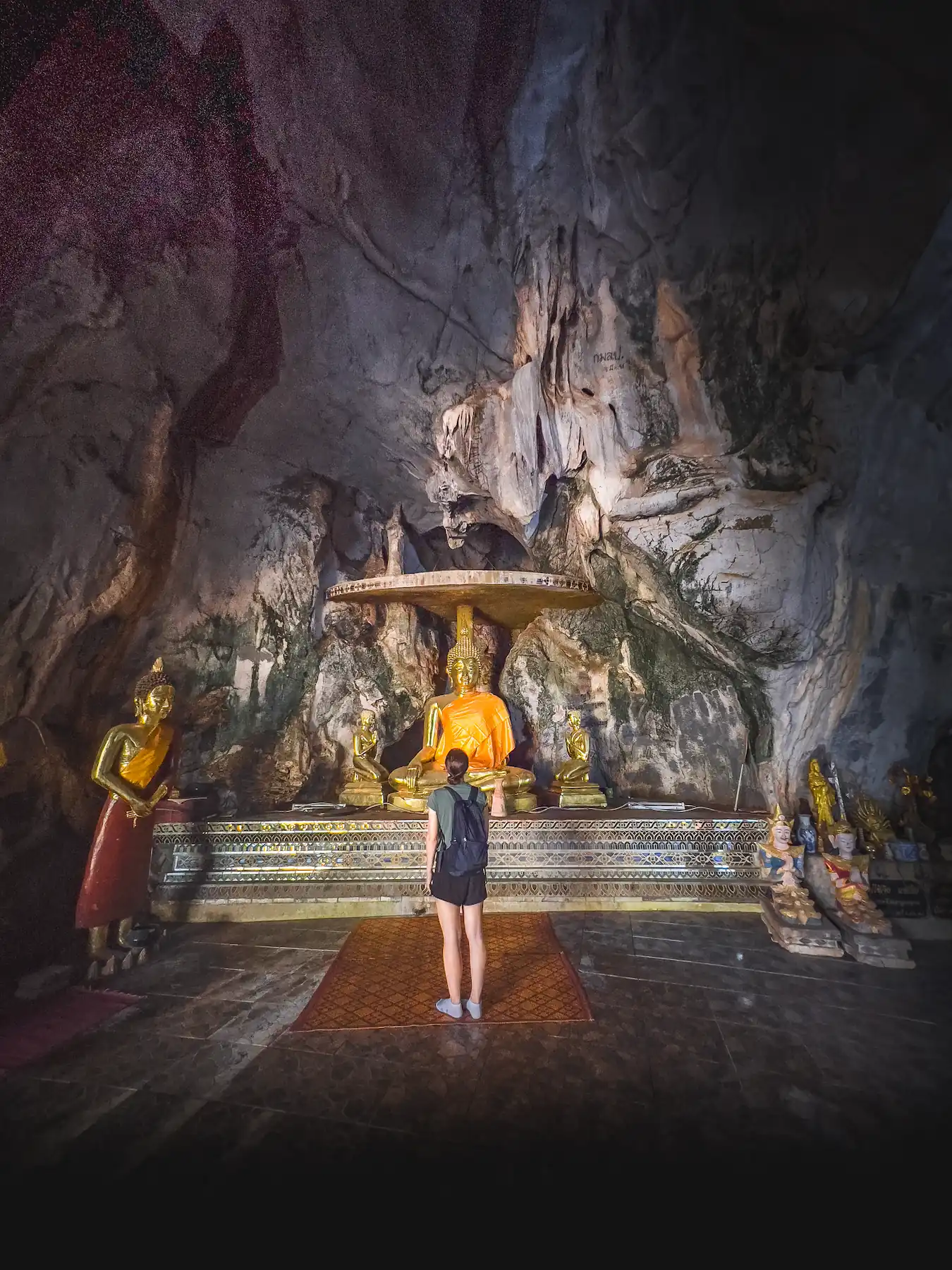 Woman looking at shrine in Buddha Cave Temple in Chiang Rai
