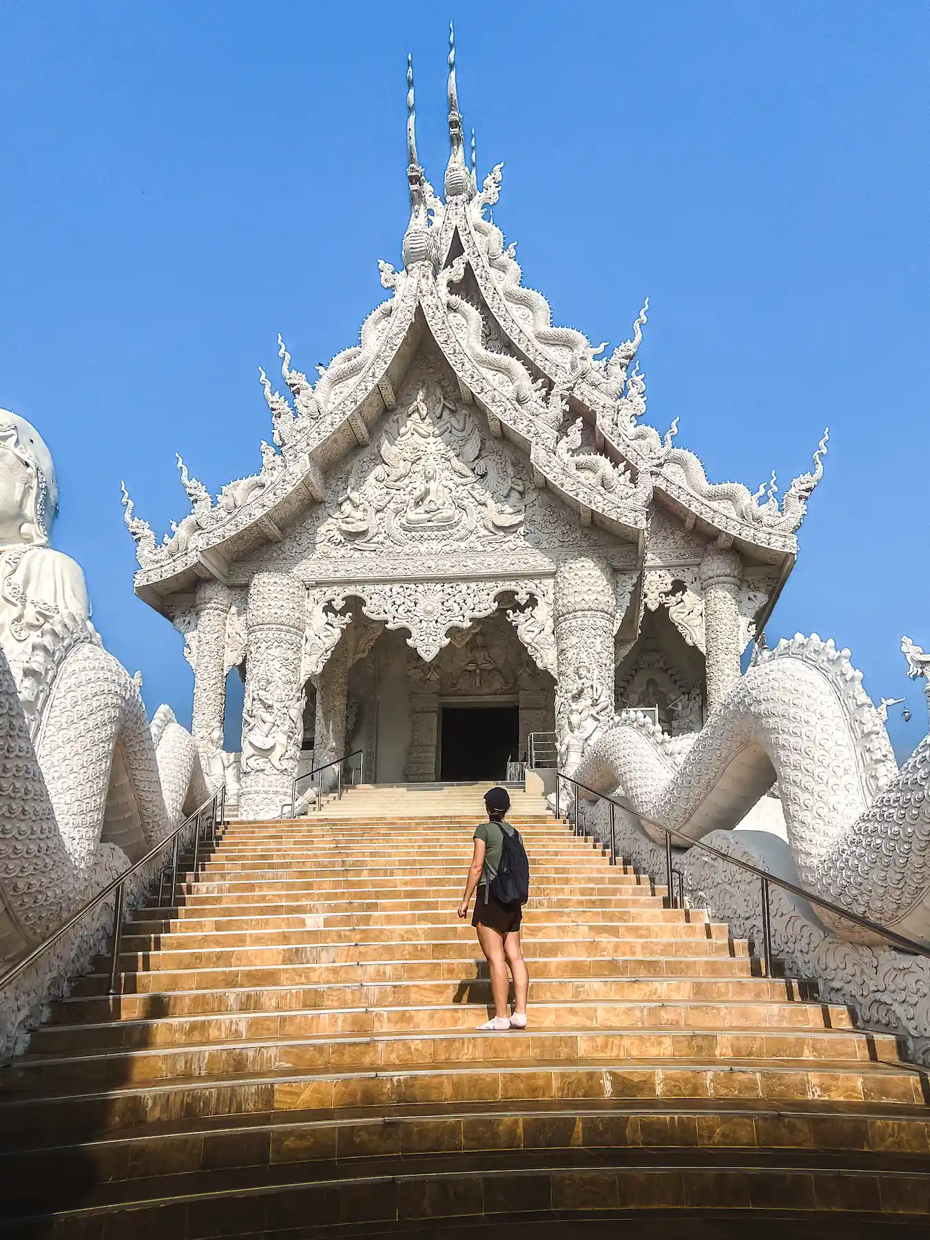 Woman on stairs looking at Gudinnestatyn Temple in Chiang Rai
