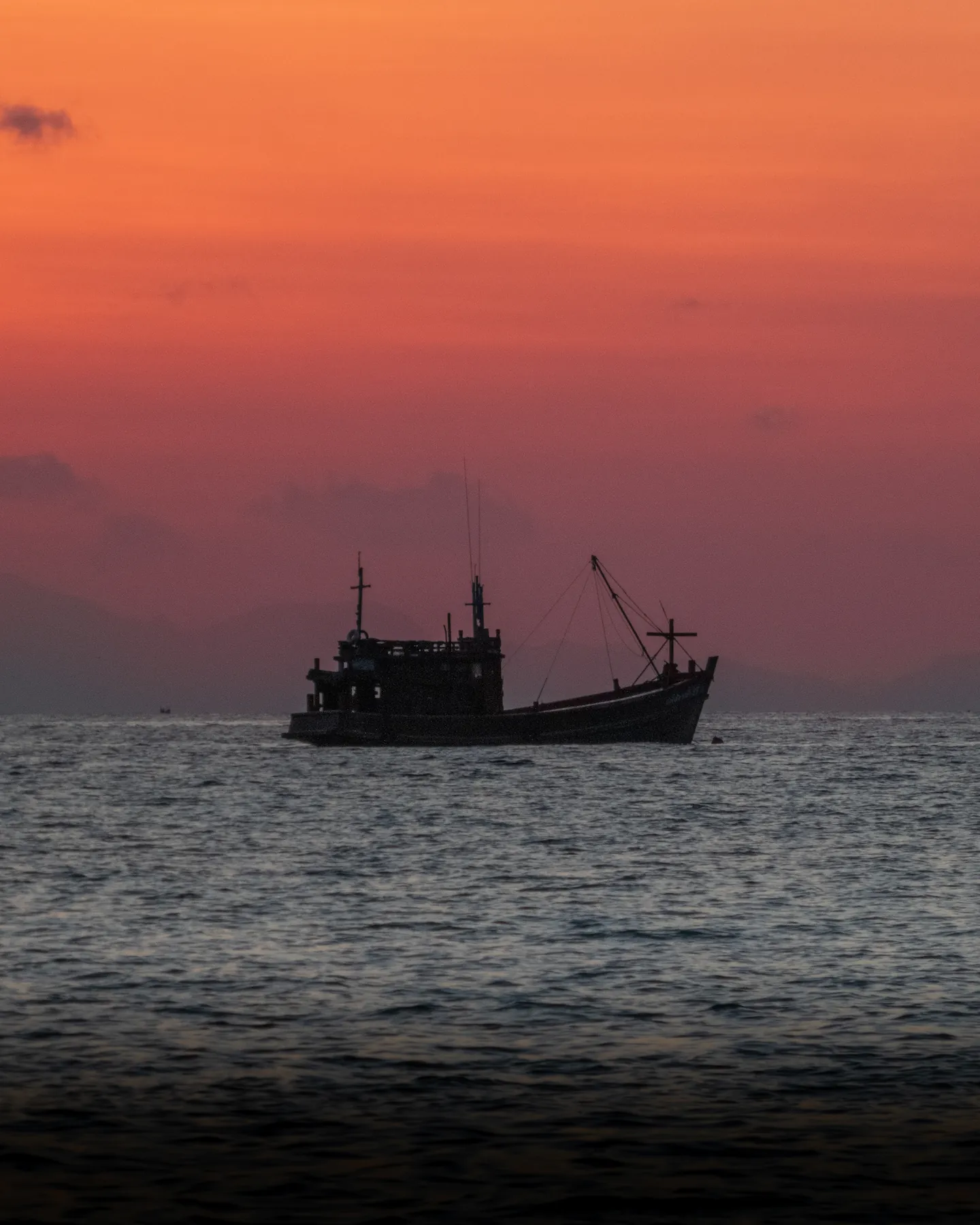 Deep red sunset behind fishing boat in the ocean