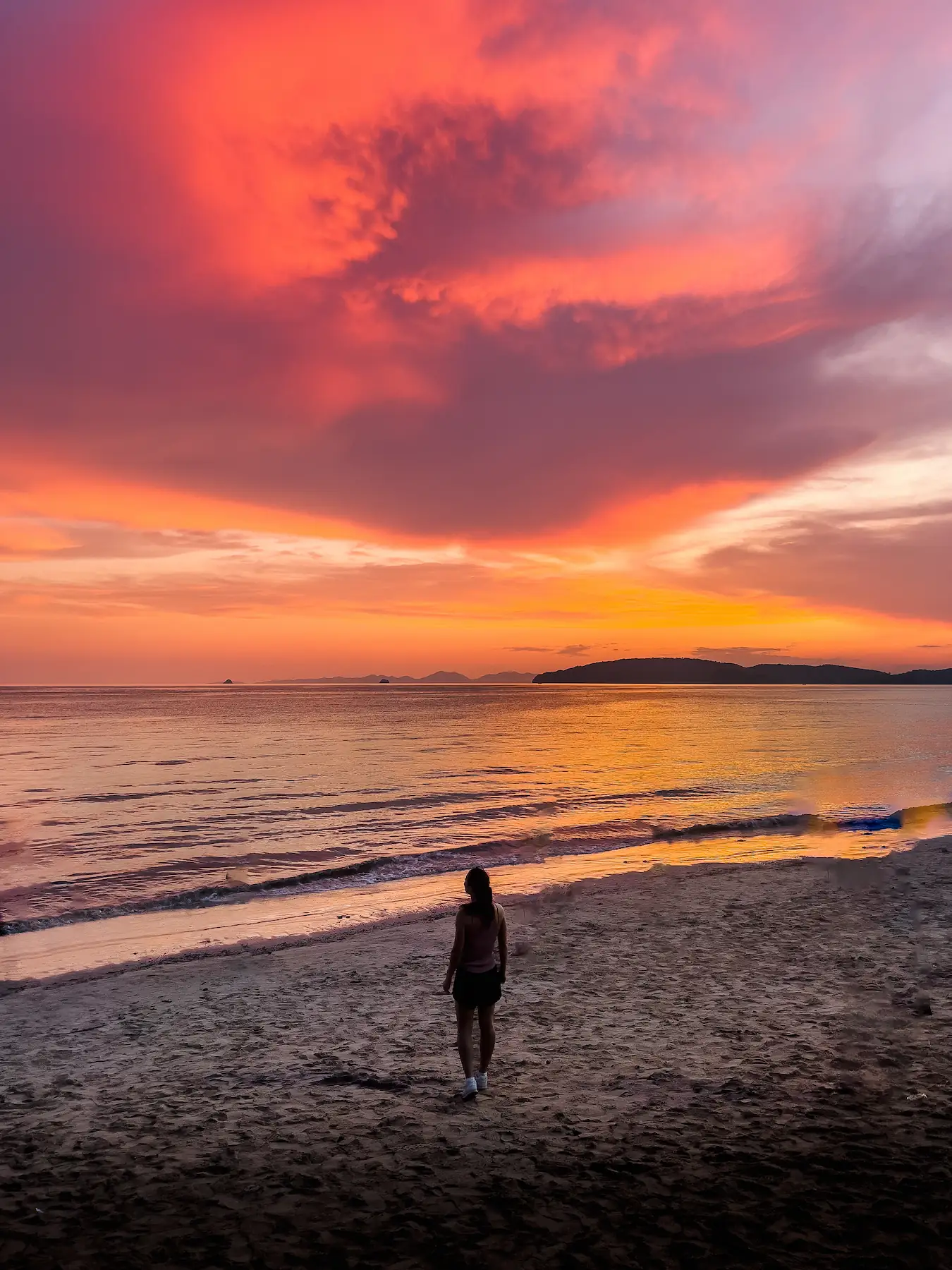 Woman on beach watching colorful sunset