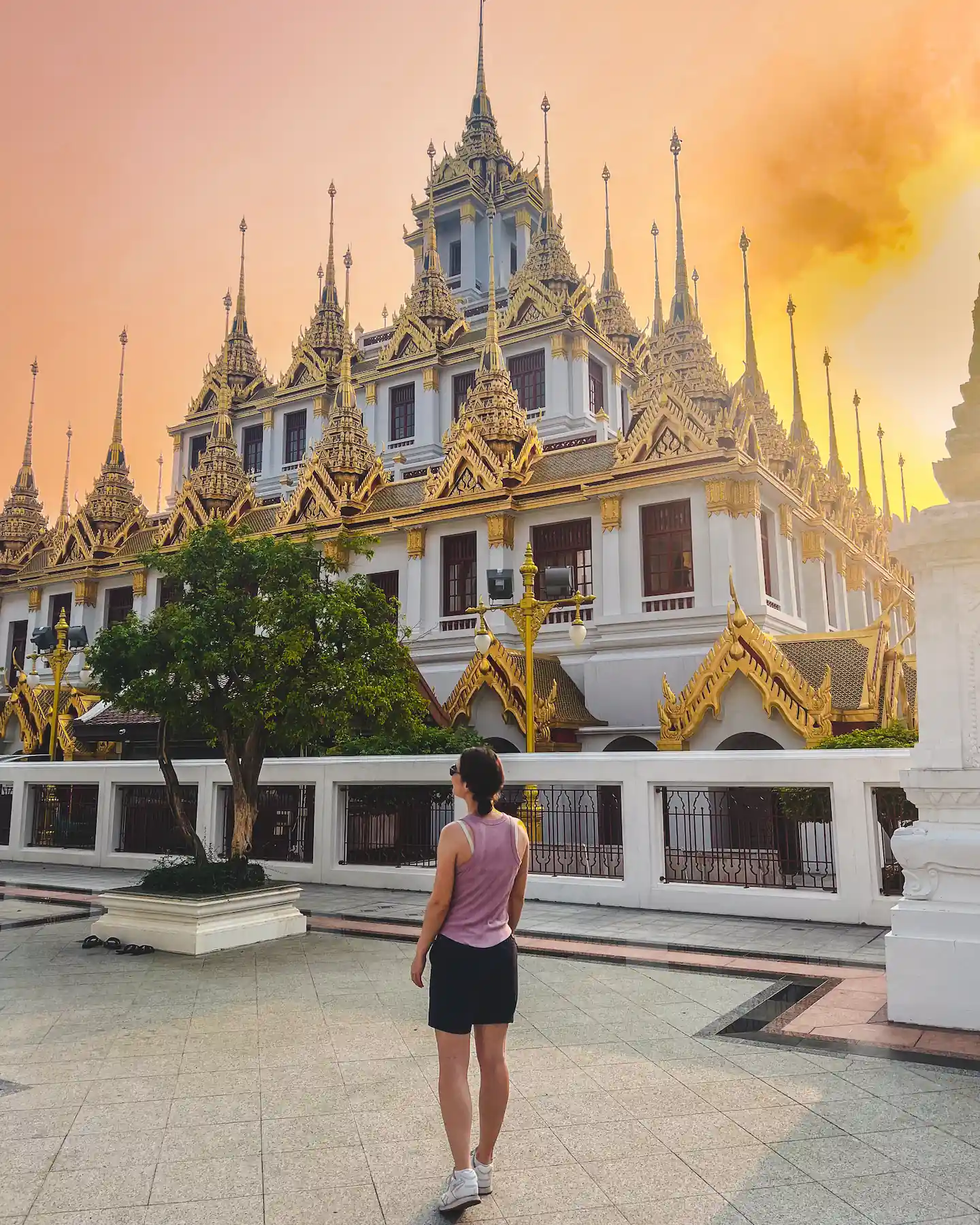 Woman looking at Thai temple during sunset
