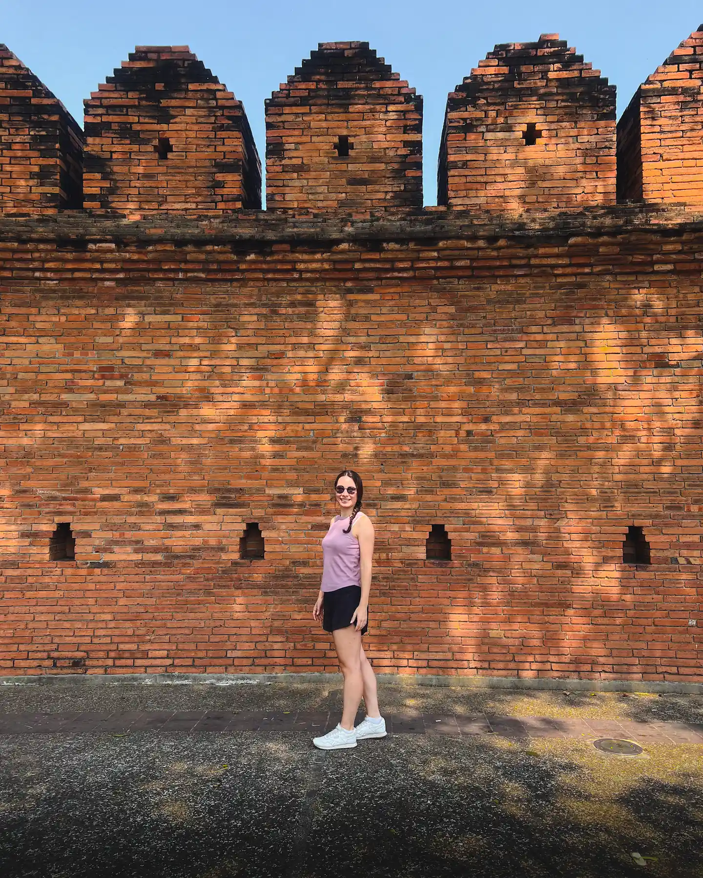 Woman smiling in front of old city wall in Chiang Mai