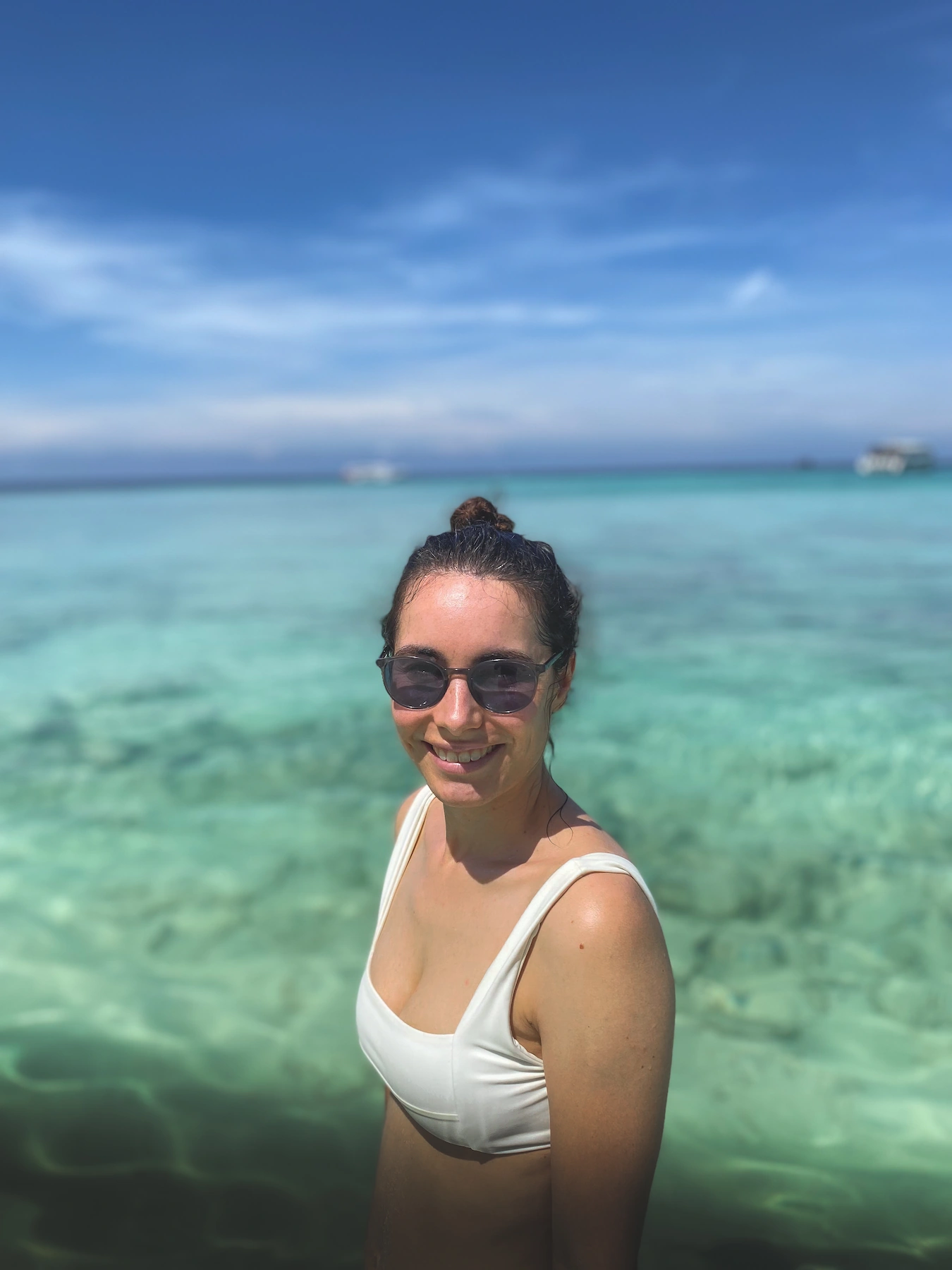 Woman smiling with the clear blue ocean behind her
