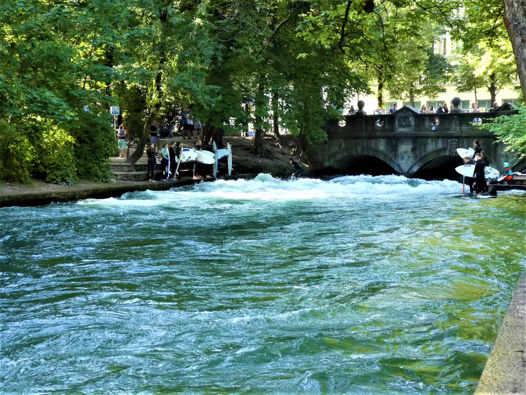 Surfers taking turns at the Eisbach wave in Munich